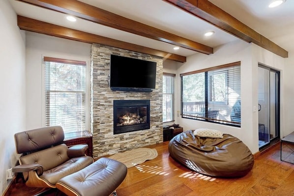 A living room with a stone fireplace, leather sofa, and a bean bag. - Sophisticated, dog-friendly condo in nature with fireplace - walk to village (Mammoth Lakes)