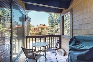 A covered porch with a table and chairs, a covered grill, and a view of a house. - Sophisticated, dog-friendly condo in nature with fireplace - walk to village (Mammoth Lakes)