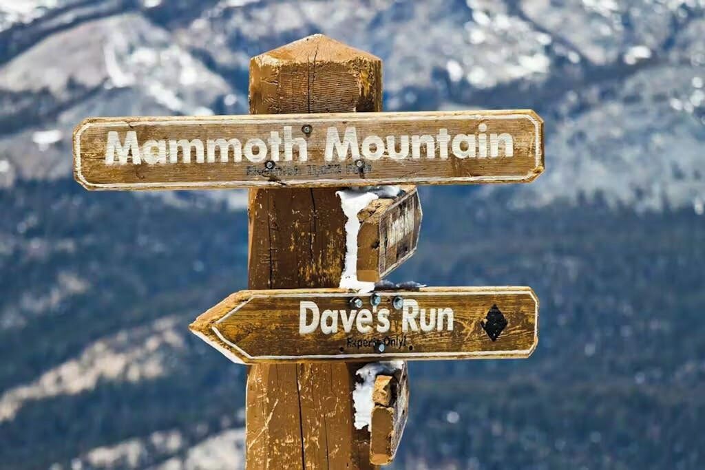 Un cartel de madera con dos indicaciones direccionales, una señalando a Mammoth Mountain y la otra a Dave's Run.