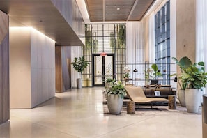 A modern lobby with a reception desk, seating area, and large windows. - Modern 1BR Oasis with Pool & Gym Access (Miami)