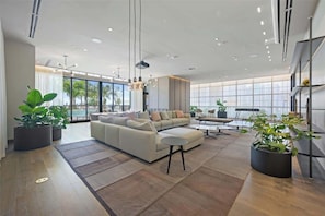 A spacious living room with a large sofa, coffee table, and potted plants. - Modern 1BR Oasis with Pool & Gym Access (Miami)