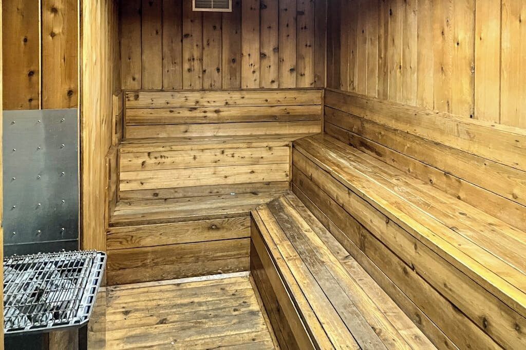 A wooden sauna with benches and a metal grate.