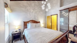 Une chambre à coucher avec un lit en bois, une table de chevet et une armoire.