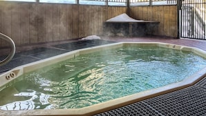 Un bain à remous doté d’une banquette en bois et d’une rambarde en métal, entouré d’une clôture en bois et d’un portail en métal.