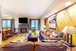 A living room with a fireplace, a television, a sofa, and a dining area with a table and chairs. - Updated Ground-floor Condo with On-site Pool, Hot Tub, Sauna, & Tennis Courts (Mammoth Lakes)