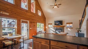 A spacious kitchen with a large island, wooden cabinetry, and a fireplace. - Sunlit, dog-friendly home with hot tub, gas fireplace, & washer/dryer (Dover)