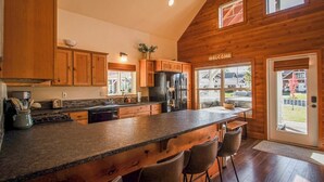 A spacious kitchen with wooden cabinets, a central island, and a 'WELCOME' sign. - Sunlit, dog-friendly home with hot tub, gas fireplace, & washer/dryer (Dover)