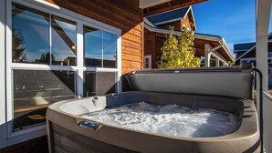 A hot tub in a wooden cabin with large windows and a view of other cabins. - Sunlit, dog-friendly home with hot tub, gas fireplace, & washer/dryer (Dover)