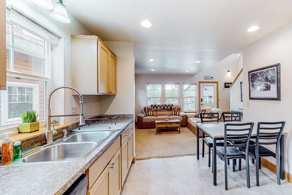 A kitchen with a sink, cabinets, and a dining area with chairs and a table.