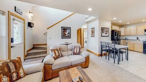 A living room with a sofa, coffee table, and a staircase leading to a kitchen area.