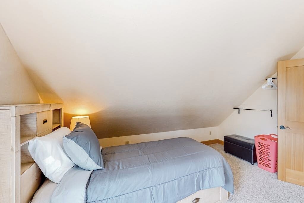 A bedroom with a bed, a nightstand, a lamp, a closet, and a small storage unit.