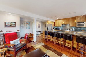 A modern kitchen with a central island, wooden cabinets, and bar stools. - All-season condo with hot tub, deck, sauna, wood stove & washer/dryer (Mammoth Lakes)