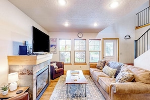 A living room with a fireplace, a television, a sofa, and a coffee table. - Home with patio, grill, fireplace, streaming, washer/dryer & AC (Dover)
