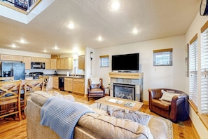 A spacious living area with a fireplace, a television, and a dining area with wooden furniture. - Home with patio, grill, fireplace, streaming, washer/dryer & AC (Dover)