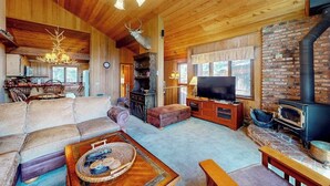 A cozy cabin interior with a fireplace, wooden furniture, and a television. - Mountain view condo with pool, hot tub, sauna & tennis - near ski lifts & golf (Mammoth Lakes)