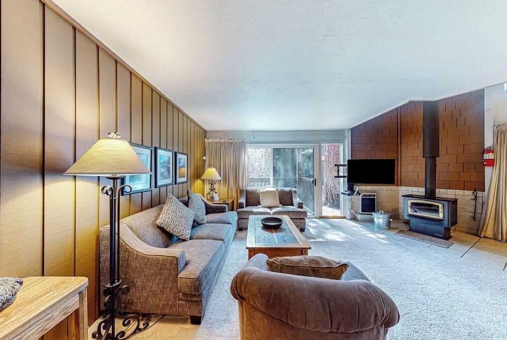 A living room with a sofa, armchair, coffee table, lamp, fireplace, and a television.