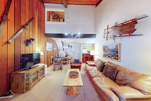 Ein gemütliches Wohnzimmer mit einem Holztv-Schrank, einer Ledersofa und einem Essbereich mit Tisch und Stühlen.