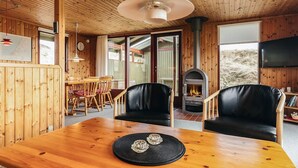 Un interior de madera con una mesa de comedor, sillas, chimenea y televisor.