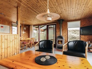 A wooden interior with a dining table, chairs, a fireplace, and a television. - 6 Person Holiday Home in Lokken (Lokken)