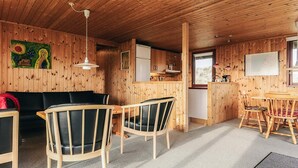 Interior de una cabaña de madera con comedor, cocina y sala de estar.