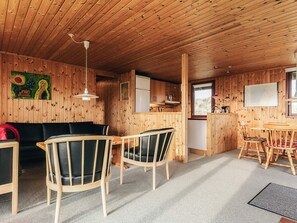 A wooden cabin interior with a dining area, kitchen, and living room. - 6 Person Holiday Home in Lokken (Lokken)