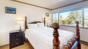 A bedroom with a bed, nightstands, and a window with a view.