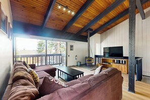 Ein Wohnzimmer mit Holzbalkendecke, einer Couch, einem Fernseher und einem Kamin.