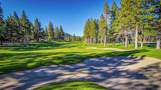 A golf course with a clear path, sand bunkers, and trees.