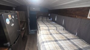 A compact room with a bed, a small kitchenette, and a wooden bench. - Peaceful 1-bedroom caravan with AC in Mammoth Spring. (Mammoth Spring)