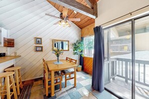 Ein Essbereich mit Holztisch und Stühlen, Deckenventilator, Spiegel und einem Fenster mit Vorhängen.