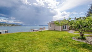 Ein Haus mit Steg, einem Rasen und Blick auf einen See und Berge.