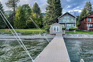 A dock leading to a house with a small shed, surrounded by water and trees. - Lakefront home and studio with kayaks, dock, WiFi, fireplaces, BBQ grill (Hope)