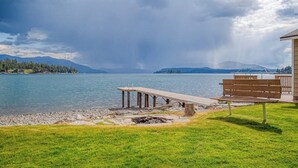 Näkymä järvelle, jossa on puinen laituri, penkki ja parvekkeellinen rakennus.