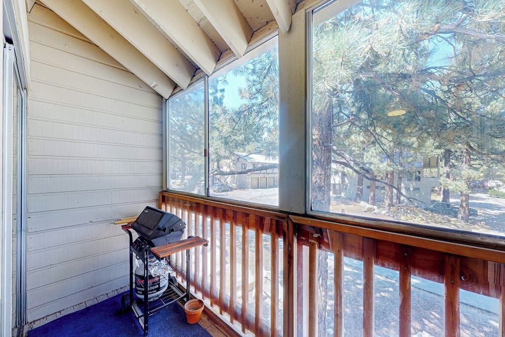 A covered porch with a view of trees and a building.