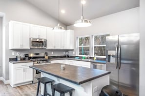 A modern kitchen with white cabinets, stainless steel appliances, and a central island with bar stools.