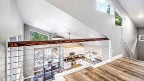 A modern interior with a staircase, a kitchen, and a dining area. - Secluded home with deck, grill, hot tub, fireplace, private beach, & W/D (Sagle)