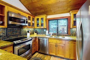 Eine Küche mit Holzschränken, einem Edelstahlkühlschrank, einem eingebauten Backofen und einem Geschirrspüler.