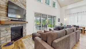 Ein modernes Wohnzimmer mit Kamin aus Stein, einem großen Ecksofa und einem an der Wand montierten Fernseher.