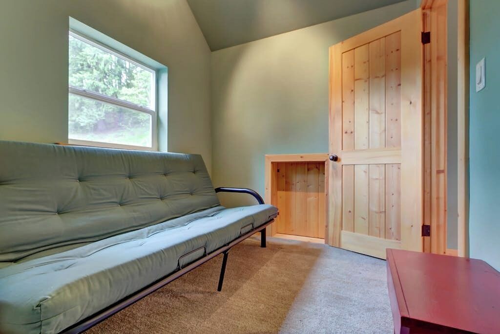 A room with a sofa, a small table, a wooden door, and a window.