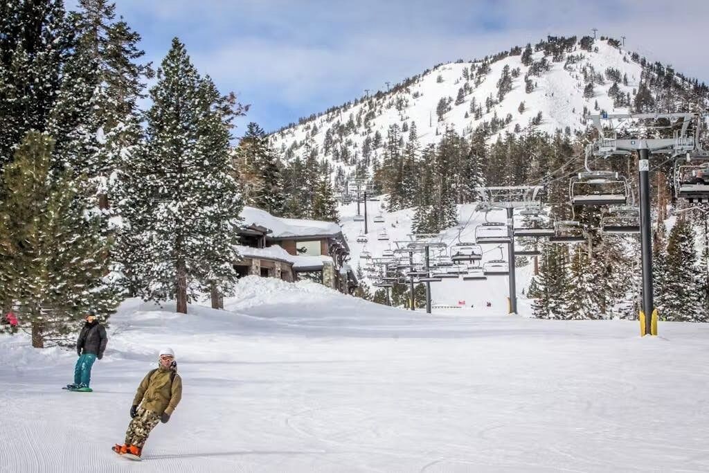 A snowy ski slope with a ski lift, trees, and a mountain in the background.