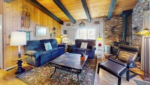 Ein gemütliches Wohnzimmer mit Holzbalken, Kamin und bequemen Sitzmöglichkeiten.