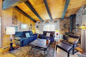Ein gemütliches Wohnzimmer mit Holzbalken, Kamin und bequemen Sitzmöglichkeiten.