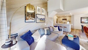 A modern living room with a sofa, ottoman, and a floor lamp. - Updated Condo With Pool and Spa Access, Near Ski Resort, Hiking/Biking Trails (Mammoth Lakes)