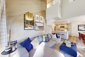 Ein modernes Wohnzimmer mit einer Couch, einem Hocker und einer Stehlampe.