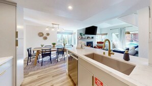 A modern kitchen with a large island, a dining area with chairs, and a view of the living room. - Updated Condo With Pool and Spa Access, Near Ski Resort, Hiking/Biking Trails (Mammoth Lakes)