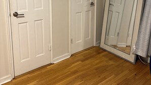 A room with two white doors, wooden flooring, and a mirror on one wall.