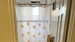 A bathroom with a shower curtain, a towel rack, a toilet, and a patterned rug.