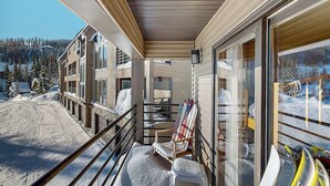 Un balcon abrité offrant une vue sur un paysage enneigé, avec une chaise et un kayak.