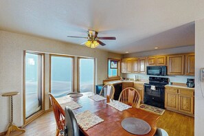 A kitchen with wooden cabinets, a microwave, an oven, and a dining area with a table and chairs.