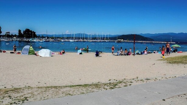 Une plage avec des tentes, des gens et des bateaux dans l’eau.